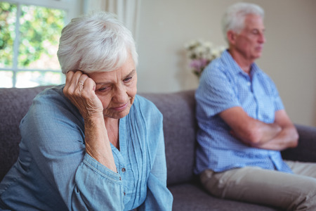 Thoughtful senior woman sitting on sofa at homeの写真素材