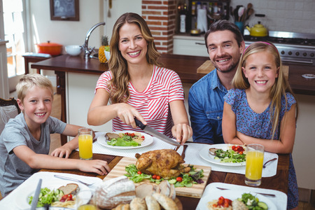 Portrait of smiling family sitting at dining tableの写真素材