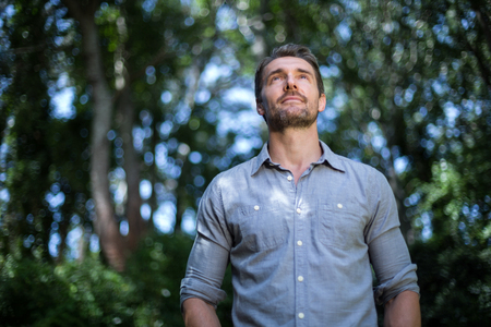 Young man day dreaming while standing in back yardの写真素材