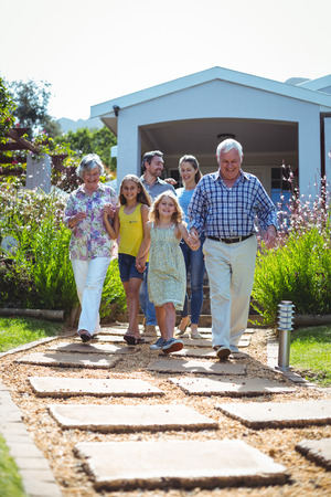 Laughing multi-generation family walking on footpath against houseの写真素材