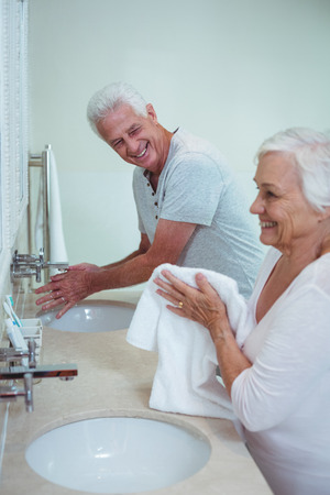 Happy senior couple cleaning hands while standing in bathroomの写真素材