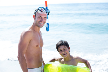 Portrait of smiling father and son with swimwear at beachの写真素材