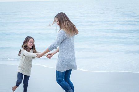 Happy mother and daughter playing at sea shoreの写真素材