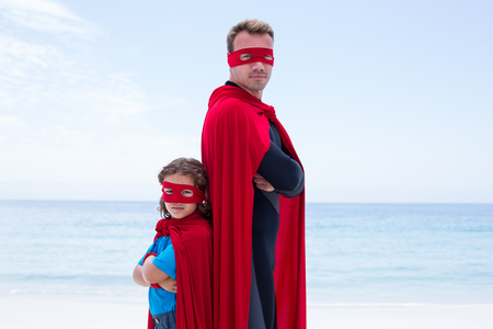 Portrait of confident man and son standing back to back sea shoreの写真素材