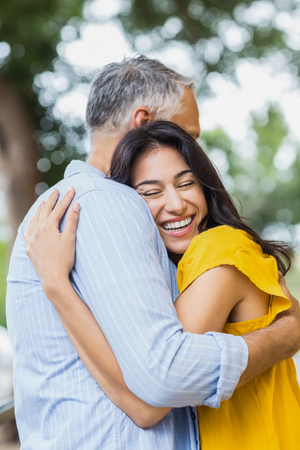 Happy woman hugging man while standing outdoorsの写真素材