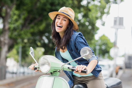 Portrait of woman sitting on moped in cityの写真素材