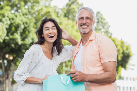 Portrait of happy couple with shopping bags standing outdoorsの写真素材