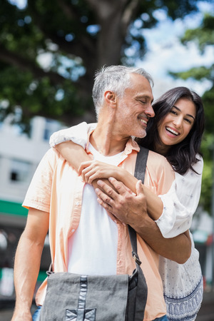 Portrait of happy woman embracing man from behind in cityの写真素材