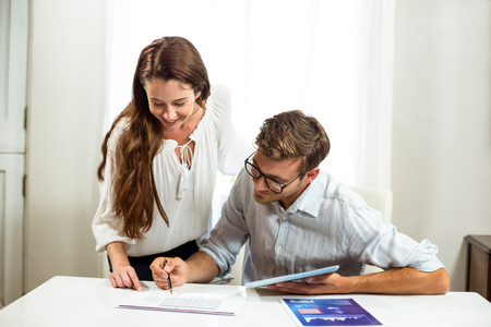 Male and female collegues discussing at desk in officeの写真素材