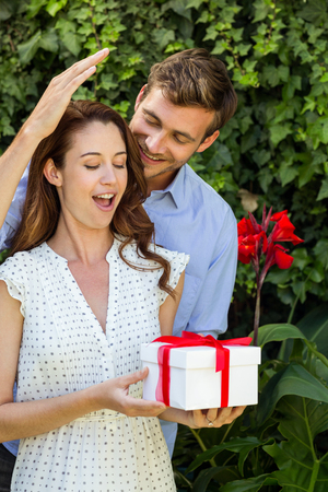 Happy man giving gift to woman at front yardの写真素材