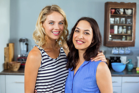 Portrait of smiling young women standing in kitchen at homeの写真素材