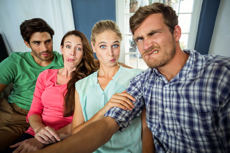 Friends making funny facial expressions at homeの写真素材