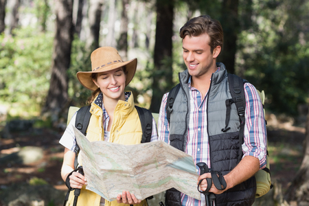 Couple looking at map while standing in forest during hikingの写真素材