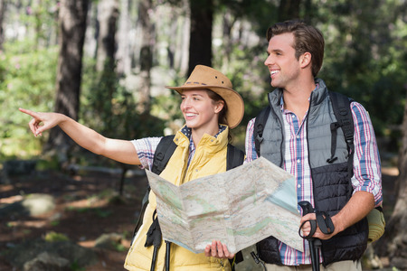 Woman pointing away with partner while holding map during hiking