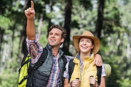 Young man pointing away with partner during hiking in forestの写真素材
