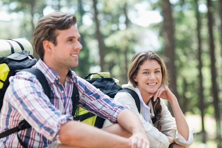 Portrait of woman sitting with partner in forest during hikingの写真素材