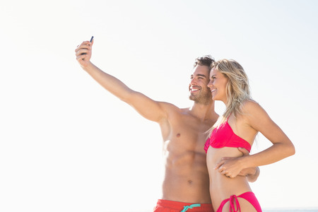Happy couple taking a selfie on the beachの写真素材