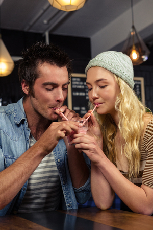 Couple sharing a milkshake in a coffee shopの写真素材