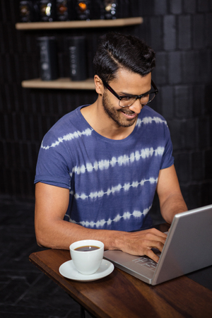 Man using a laptop in a coffee shopの写真素材