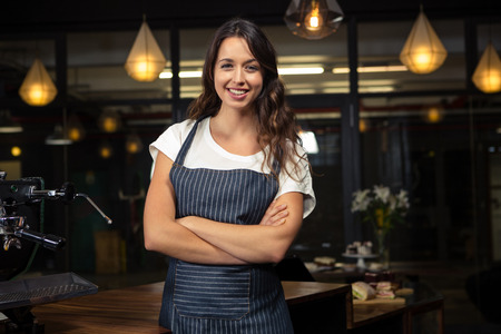 Pretty barista crossing arms in coffee shopの写真素材
