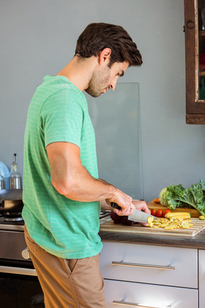 Man chopping vegetables in kitchenの写真素材