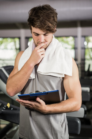 Gym instructor looking at clipboard in gymの写真素材