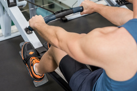 Man exercising on rowing machine at gym