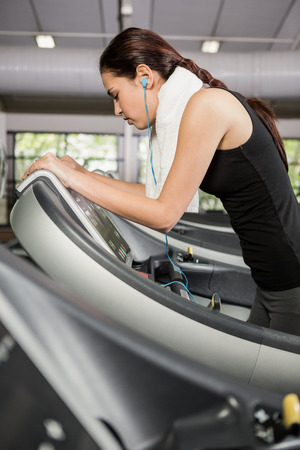 Woman listening to music on treadmill at gymの写真素材