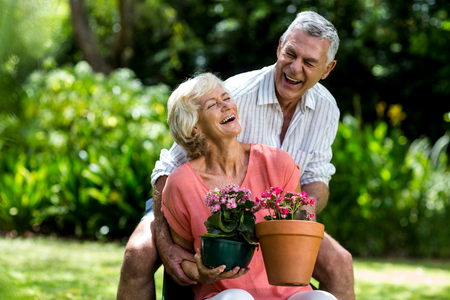 Senior couple with flower pots enjoying in yardの写真素材