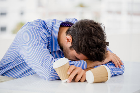 Businessman putting his head down on desk in officeの写真素材