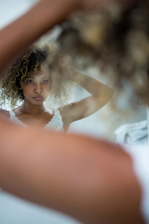 Woman looking at mirror in bathroomの写真素材