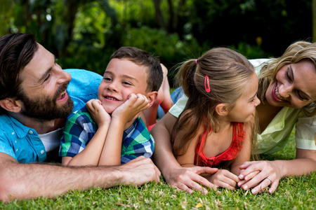 Happy parents lying with children on grass in yardの写真素材