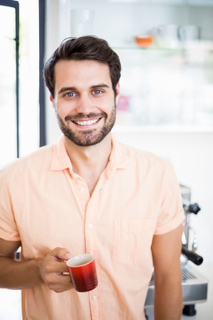 Portrait of man holding coffee cup in the kitchenの写真素材
