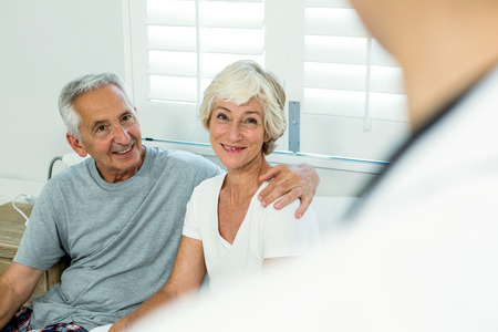 Smiling senior man and woman with doctor at homeの写真素材