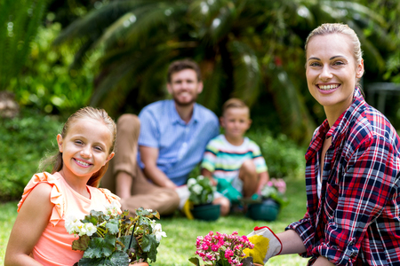 Portrait of smiling mother and daughter with flower pots in yardの写真素材