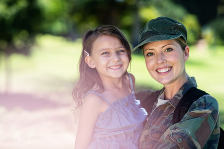 Portrait of happy soldier reunited with her daughter in the park on a sunny dayの写真素材