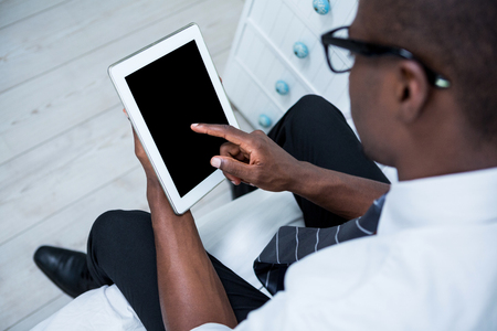 Man using digital tablet on bed in bedroomの写真素材