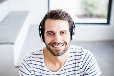 Portrait of happy man listening to music on headphone at home