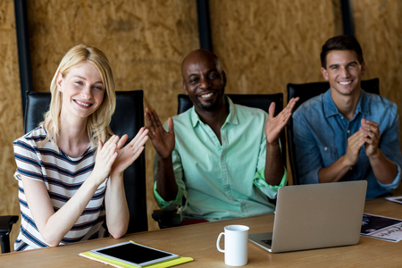 Portrait of colleagues applauding at their desk in the office