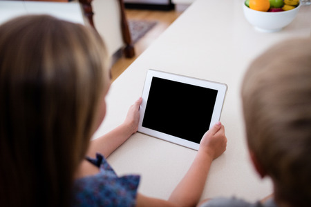 Siblings using digital tablet at homeの写真素材