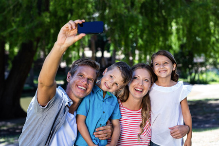 Happy family in park taking a selfie on the mobile phone