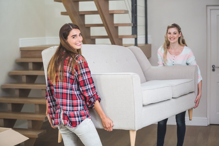 Portrait of friends shifting sofa together in the new houseの写真素材