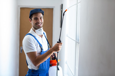 Portrait of happy pesticide worker with sprayer at homeの写真素材