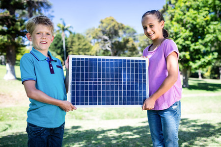 Portrait of siblings holding a solar panel in parkの写真素材