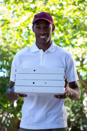 Portrait of happy delivery man holding pizza boxesの写真素材