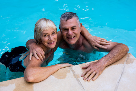 Happy senior couple swimming in poolの写真素材