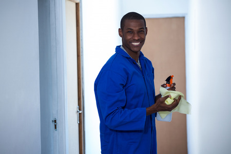 Happy handyman holding spraying insecticide and napkin at homeの写真素材