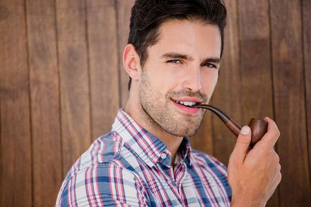 Portrait of young man smoking pipe on a wooden backgroundの写真素材