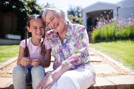Grandparents and granddaughters sitting in the garden on a sunny dayの写真素材