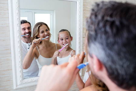 Parents and daughter brushing their teeth in the bathroom at homeの写真素材